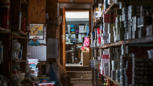 Cluttered storage room with shelves of supplies and a calendar on the wall.