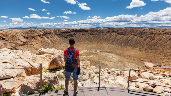 Man standing at the edge of a huge impact crater.