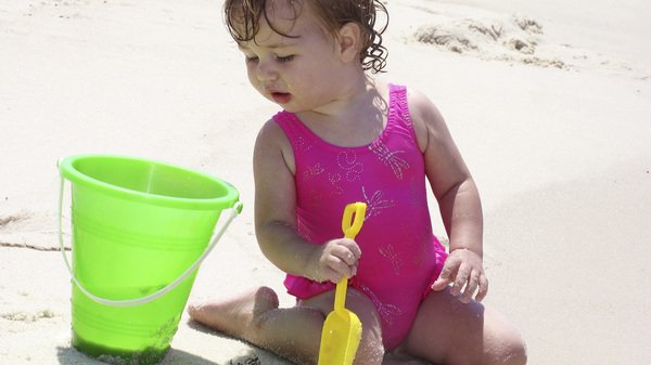 Kleinkind am Strand mit Schaufel und Eimer