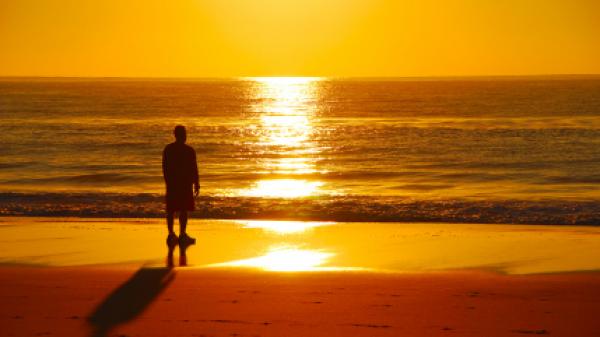 Solitary figure overlooking ocean at sunrise.