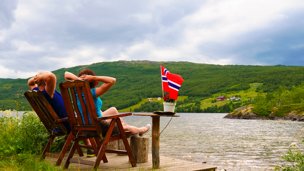 Couple relaxing by the river with Norwegian flag beside them.