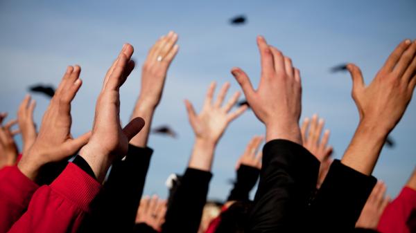 Group of people with arms raised above heads.