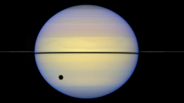 Saturn's rings seen edge-on by the Hubble Space Telescope. The large spot is the shadow of Saturn's moon Titan.