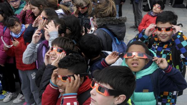 Children watching a solar eclipse wearing protective tinted glasses.