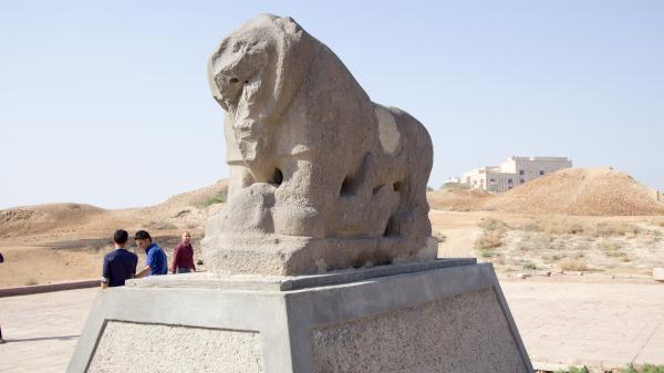 3 men next to the black basalt statue of the lion of Babylon which depicts a lion standing above a laying human in today's Iraq. March 20, 2015.