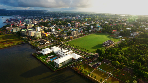 Areal view of Suva, capital of Fiji, on the waterfront with buildings and palm trees, and Albert park sports field.