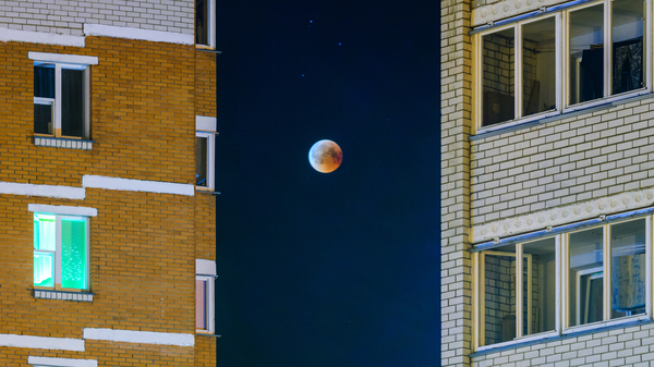An eclipsed Moon, framed between two buildings