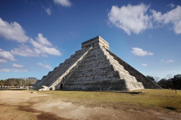 Maya temple pyramid with sunlight and shadows forming the shape of a slithering snake on the staircase