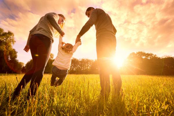 Parents playing with their young daughter in the evening sun