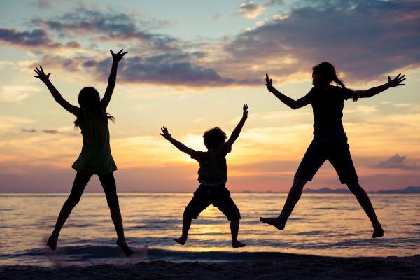 Children jumping on the beach at sunset