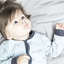 Close up of dark-haired child laying in bed looking up. 