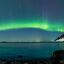 A vivid green aurora arc visible over Harstad, northern Norway.
