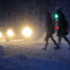 Two people walking in bad winther weater, cars approaching them.