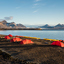 Colorful tents at a remote campsite in Svalbard under the midnight sun, surrounded by Arctic mountains and snow patches.