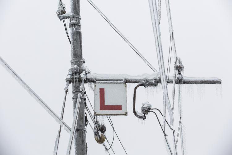 Frozen electrical lines for railroad with icicles and a sign with the letter L.