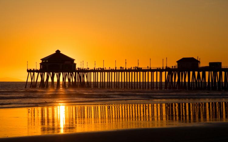 Pier silhouetted against the sunset on a California beach.