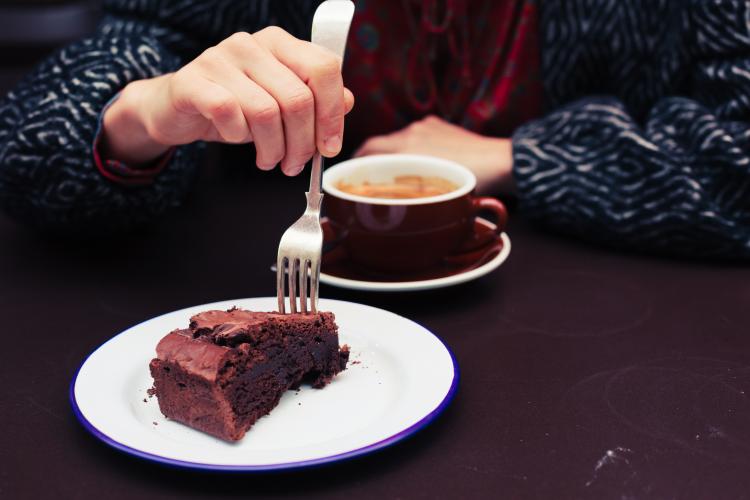  egy nő csokoládétorta és kávé mellett.