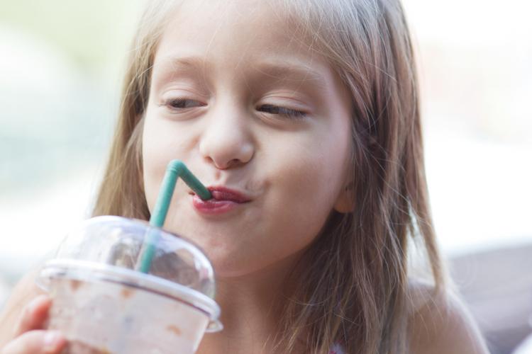 Girl drinking milkshake in a cafe outdoors.