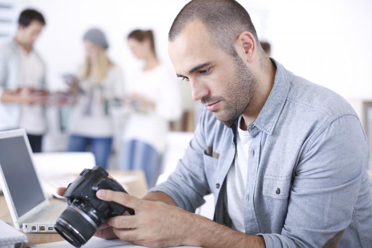 Man sitting at his desk with a computer and a camera.