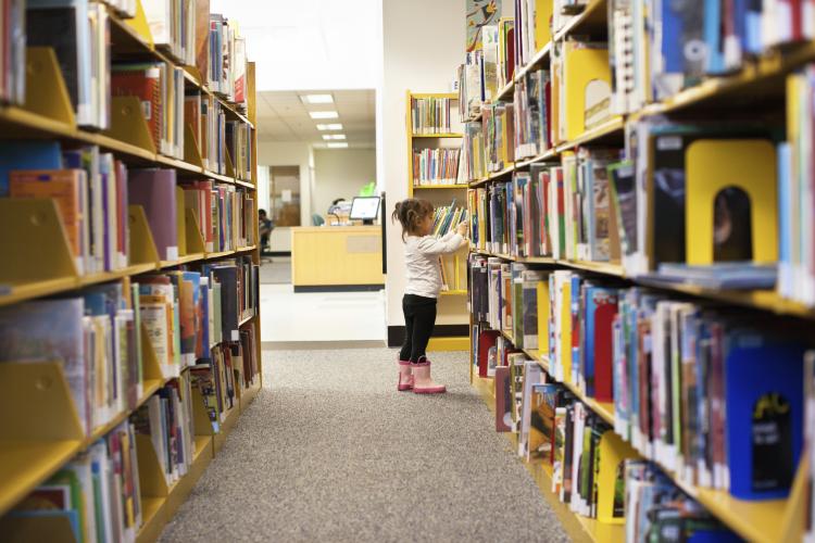 Girl at the library picking a book.