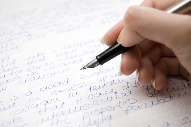 Hand with pen writing a letter.