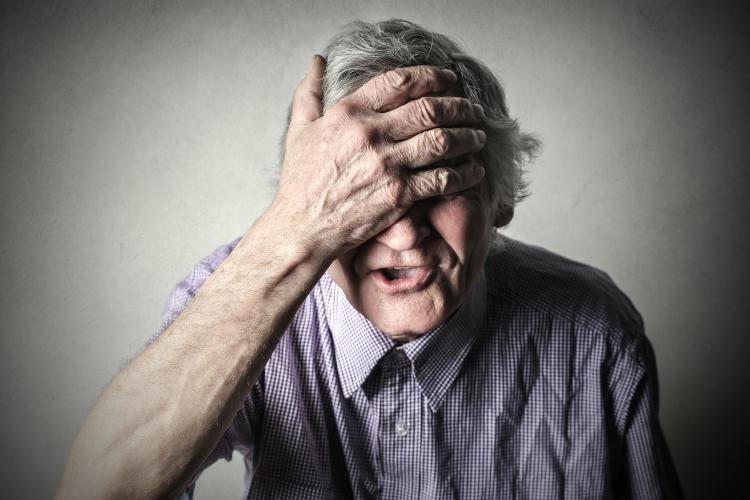 A man slapping his forehead because he forgot something.