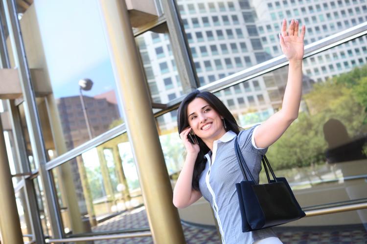 A business woman waving goodbye at an office building.