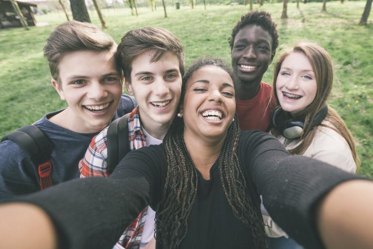 A group of teenagers laughing and taking a selfie.