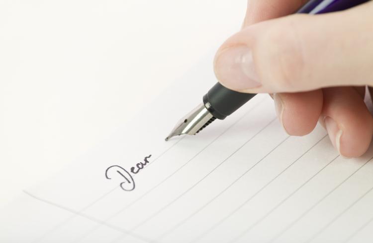 Hand and pen writing a letter.