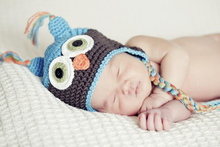 Newborn baby sleeping in owl hat.