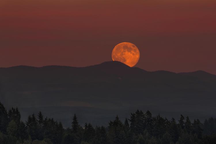 Full Moon rising over Oregon mountain range landscape at dusk.