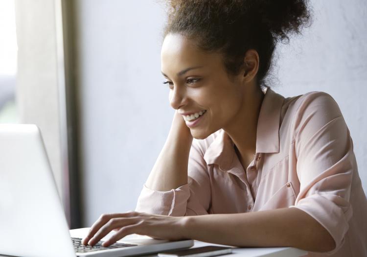 Beautiful young woman smiling and looking at laptop screen.