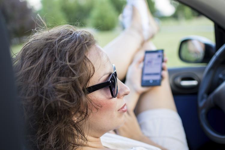 Woman in a car with her legs out the window.