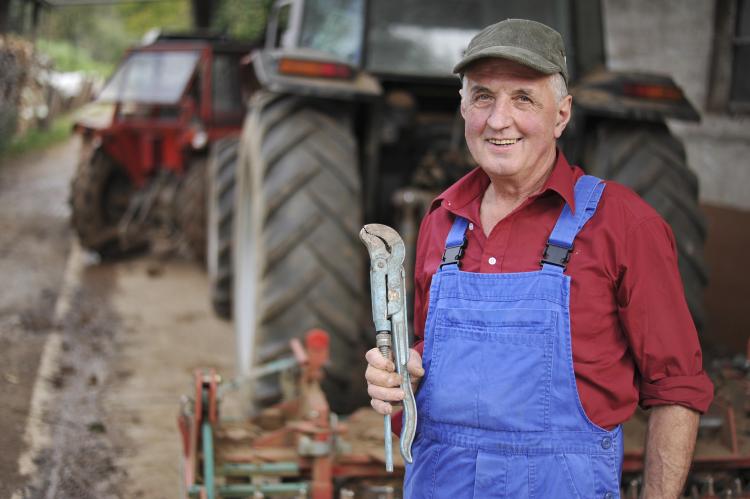 Farmer repairing his red tractor.