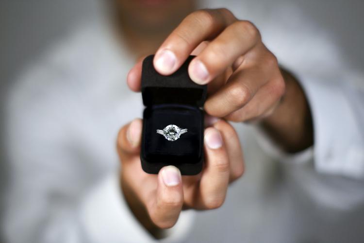 Hands presenting an engagement ring.