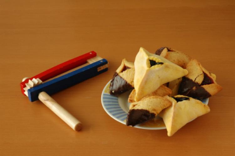 En tallerken med hamantashen, trekantformede kaker, og en grogger, en bråke-leke som brukes ved den jødiske helligdagen Purim.