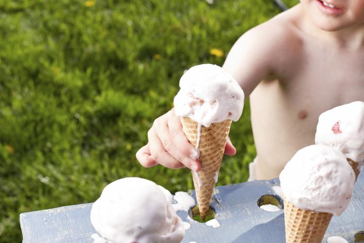 Child getting a strawberry ice cream cone.