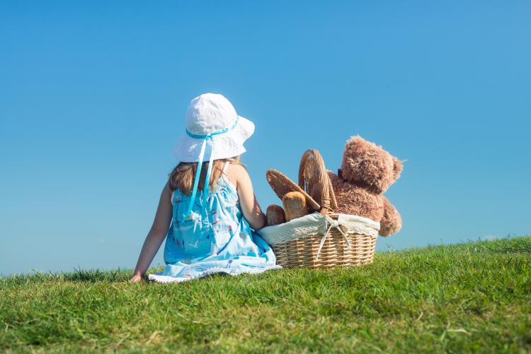 A girl with a teddy bear in a basket.