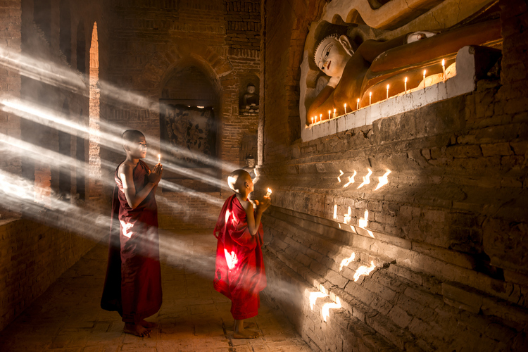 Two young monks praying inside the temple in Bagan, Myanmar