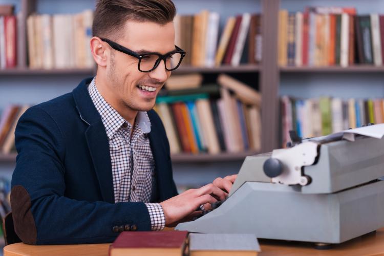 Happy young author working on a typewriter.