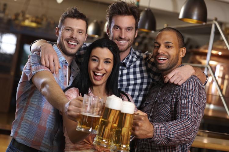 Group of happy friends clinking with beer in pub.